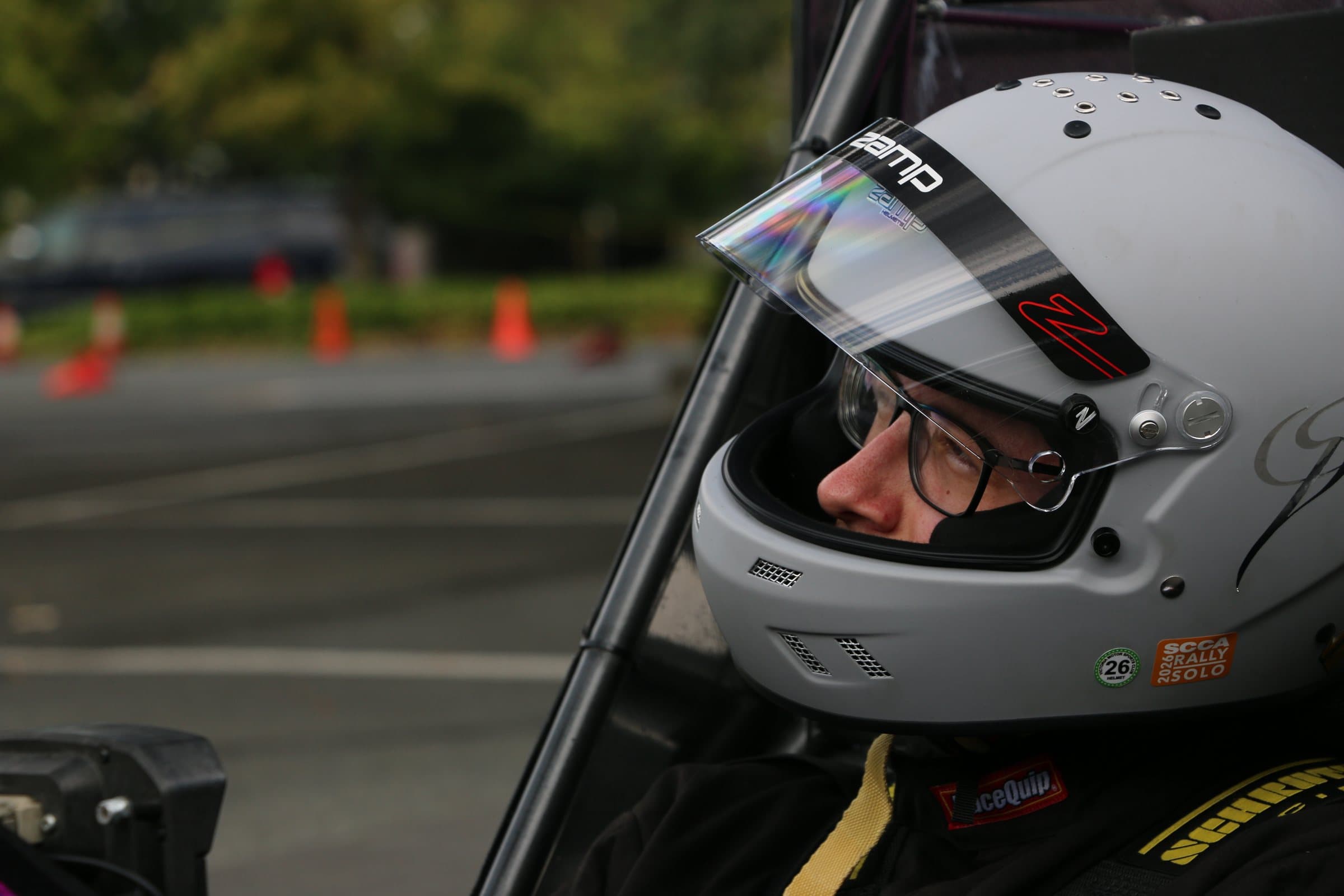 Russell Bilinski in a helmet and harness, seated in the cockpit of a formula-style race car at a cone course