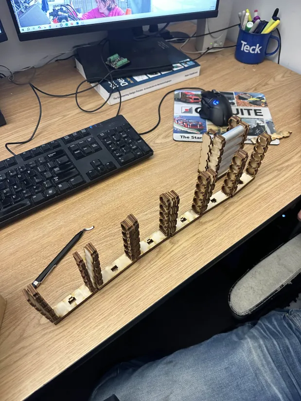 Laser-cut mock Enepaq brick with aluminum rods on desk